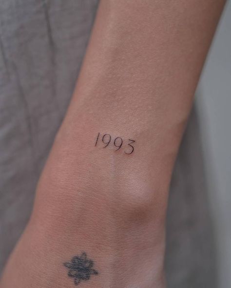 "1993" lettering tattoo located on the wrist. Unique Birth Year Tattoo, 1993 Tattoo Design, Birth Year Tattoo Wrist, 1937 Tattoo, 1991 Tattoo Design, 1993 Tattoo Ideas, Anniversary Date Tattoo Ideas, 1982 Tattoo, 1989 Tattoo