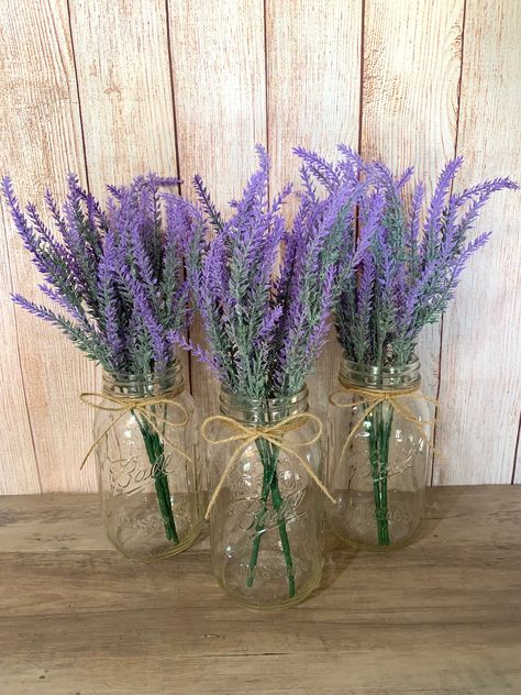 "These Lavender mason jars are perfect for wedding Centerpieces and bridal shower decor. These jars are also a great addition to your home decor, use as centerpieces or simple table decor.  Mason Jars are Quart Size Jars with twine attached at the top. Each jar has two purple faux lavender stems.  Lavender Bouquet is 14\" L Click my shop link below if you are interested in more styles of Mason Jars!  https://www.etsy.com/shop/TheCraftingJar" Rustic Table Decor Wedding, Purple Flower Centerpieces, Purple Table Settings, Centerpiece Purple, Lavender Centerpieces, Lavender Wedding Theme, Purple Party Decorations, Farmhouse Wedding Decor, Mason Jar Centerpiece