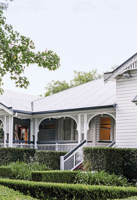 A white weatherboard Queenslander home surrounded by landscaped low hedges. Queenslander Homes Exterior, French Provincial Farmhouse, Brunswick House, Queenslander House, Stone Mansion, Australian Homes, Underfloor Heating, Colonial House, Brickwork