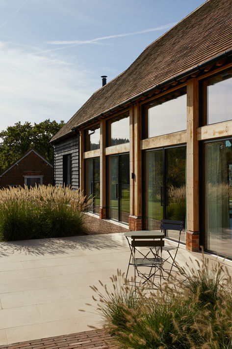 Large glass windows and pivot doors inset into the oak frame construction in this sensitive barn conversion in the Surrey Hills. Small Barn Conversion, Modern Barn Conversion, Barn Extension, Mound House, Barn Conversion Exterior, Country Architecture, Large Glass Windows, Barn Conversion Interiors, Modern Barn Style