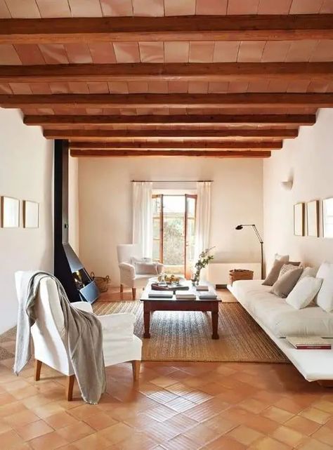 a modern rustic living room with a stained ceiling and wooden beams, a terracotta tile floor, white seating furniture, a black hearth Terracotta Tiles Living Room, Red Tile Floor, Terracotta Living Room, Terracotta Tile Floor, Tile Bedroom, Tiles Living Room, Tile Floor Living Room, Modern Rustic Living Room, Terracotta Tile