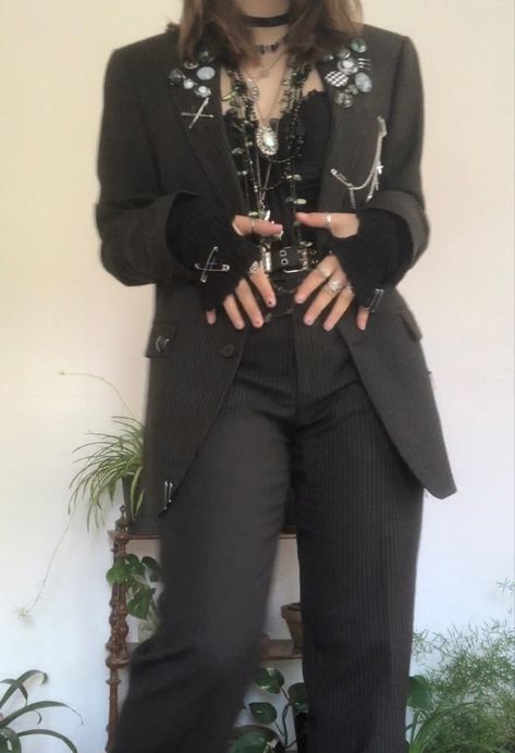 A mid-sized person/girl grey/dark green striped suit decorated with lots of oins and chains, black arm warmers, black platform dr. Martens and multiple crystal rings and bracelets. 		The person is also wearing multiple silver necklaces, a big one in form of a cross. Alternative Semi Formal, Aesthetic Suit Outfit, Corset And Suit Outfit, Alt Suit Outfit, Alt Suit Aesthetic, Punk Prom Suit, Punk Blazer Outfit, Punk Corset Outfit, Masc Goth Outfits Formal