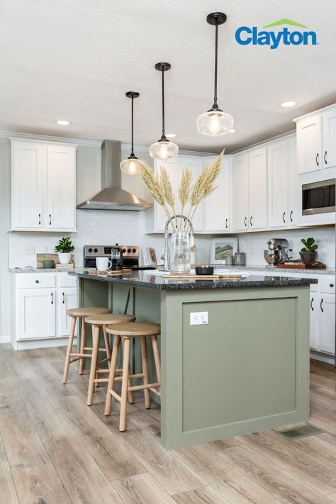 Modern kitchen with a large kitchen island with a green kitchen island with a black marble countertop, white cabinets surround the kitchen with silver handles, great granite countertops and a stainless steel range hood. Sage Kitchen Island Black Counter, Colored Island With Black Countertop, Green Cabinet With White Countertop, Green Kitchen Island Pendant Lights, Black Countertops Island, Green Kitchen Island Black Counter, Kitchen Green Island White Cabinets, Green Island With Black Countertop, White Cabinets Accent Island