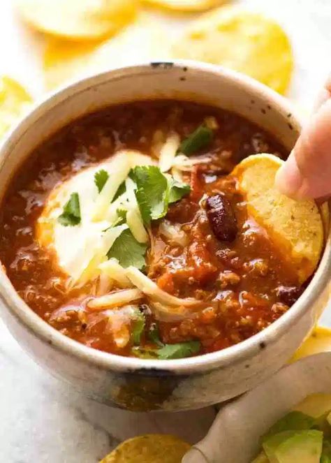 Corn chip being dipped into a bowl of Chili topped with sour cream, grated cheese and cilantro Chilli Bowl Recipe, Chilli Bowl, Chilli Con Carne Recipe, Corn Chip, Con Carne Recipe, Tomato Broth, Recipetin Eats, Chilli Recipes, Recipe Tin