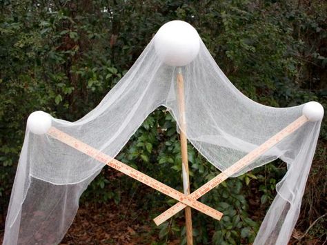 A DIY Halloween ghost is draped with gauze for a spooky front yard decoration. Halloween Cheese Cloth Ideas, Large Diy Halloween Decorations, Creepy Cloth Decorations, Outdoor Halloween Ideas Diy, Outside Halloween Decorations Yards, Diy Halloween Decorations Outdoor Yards, Halloween Yard Ideas, Cheese Cloth Ghost, Front Yard Halloween Decorations