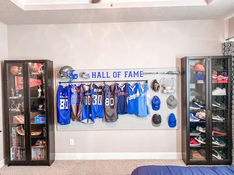 Jersey Bedroom Ideas, Display Jerseys Ideas, Sports Theme Game Room, Sports Jersey Display Ideas, Sporty Apartment Decor, Sports Metal Display Ideas, Sports Game Room Ideas, Sports Display Wall, Teenage Sports Bedroom