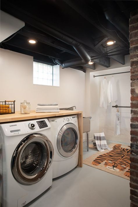 Basement laundry room with black ceiling, white walls, concrete floor, industrial pipe clothing rods, industrial stainless steel sink, wood folding table over washer and dryer Painted Concrete Floor, Sw Snowbound, Unfinished Basement Laundry, Painting Concrete Walls, Exposed Basement Ceiling, Basement Ceiling Painted, Concrete Basement Walls, Exposed Ceiling, Wood Folding Table