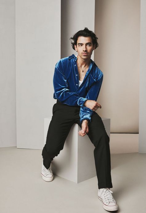 Joe Jonas, dressed in a blue button-up shirt and black pants, sits on a block with his left foot more forward than the right. He has his right hand resting on his left arm as he curiously looks towards the right. Jonas Brother, Joe Jonas, Jonas Brothers, Studio Portraits, Celebrity Pictures, Fitness Inspo, Celebrity Crush, Fashion Inspo Outfits, Celebrity Style