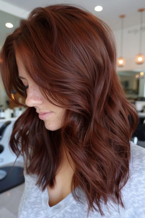 Woman with long, wavy auburn hair in a salon. Brown Hair With Red Tones, Brownish Red Hair Color Reddish Brown, Chocolate Ginger Hair, Brown Hair No Red Tones, Red Tinted Brown Hair, Red Brown Hair With Highlights, Multidimensional Brunette, Warm Chocolate Brown Hair, Brownish Red Hair