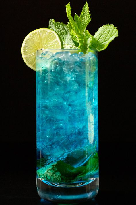 This tropical twist on the classic mojito cocktail uses blue Curacao to get its vibrant color. Mint, lime, and citrus flavors pared with rum. Recipe For Mojito, Blue Mojito, Summer Mocktails, Classic Mojito, Mango Mojito, Iced Drinks Recipes, Mint Mojito, Blue Drinks, Mojito Cocktail