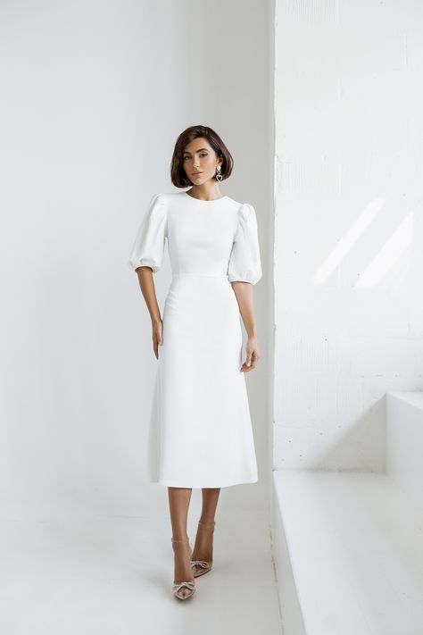 Embrace pure elegance with our White Puff Sleeve Midi Dress. The pristine white hue exudes sophistication and charm, making it a versatile choice for various occasions. The puff sleeves add a touch of drama and femininity to the classic midi length, ensuring you'll look effortlessly chic and stylish. #whitedress #puffsleeve #dress #dresses #mididress #stylish #elegant #eveningwear #eveningdress #partydress #promdress #dresslover #weddingdress #fashion White A Line Midi Dress, Casual Winter Wedding Dress Simple, White Puff Sleeve Midi Dress, White Dresses Midi, White Graduation Dress Midi, Elegant Midi Dresses Classy Chic, White Dress Classy Elegant Short, White Midi Dress Classy, Simple White Dress Classy