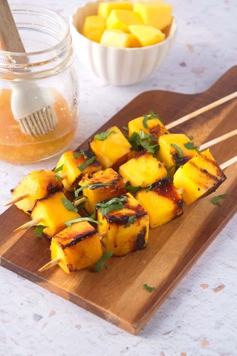 For these mango skewers, cubed mango is marinated in honey and dark rum for some Caribbean flair and then lightly charred on the grill! Recipe at inthekitch.net #inthekitch #skewers #grilledfruit