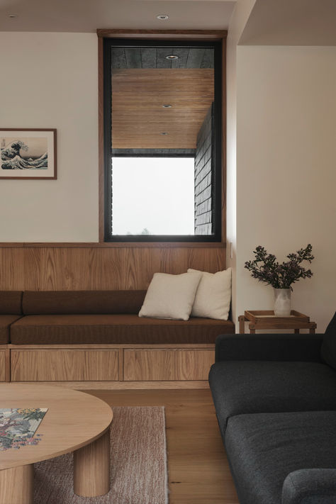 Modern living room featuring minimalist wood decor, brown built-in bench seating, and a serene design aesthetic.