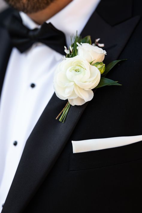 White ranunculus boutonniere with spray rose, genestra, and greenery accents. Stems partially wrapped in black velvet ribbon. PC: Ann Coen https://www.anncoen.com/photography Groomsman Flowers Groom Boutonniere, White Garden Rose Boutonniere, Boutinaire Ideas, Ranaculus Boutonniere Groomsmen, Classic Boutonniere Wedding, Modern Groom Boutonniere, Tulip Boutineer Groomsmen, Winter Wedding Boutonniere White, Neutral Wedding Boutonniere