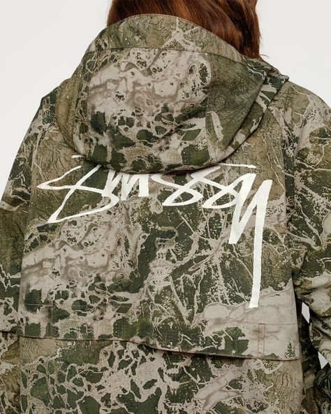 Relaxed shell jacket in nylon printed with Realtree WAV3 camo. Features a front zip closure with adjustable drawcords in the hood and hem. Stüssy smooth stock logo printed at the left chest and across the back. - #5 YKK metal zip closure with self-fabric tab - Adjustable drawcords - Front patch pocket with concealed snaps - Rear vent with interior mesh panel - Elastic cuffs - Metal eyelet vents under arms - Relaxed fit - Raglan sleeve - Unisex - Material: 100% nylon - Lining: 100% polyester - Imported Zip Up Hoodie Streetwear, Camo Zip Up, Asap Rocky Dior, Camo Clothes, Vintage Camo Jacket, Winter Camo, Football Graphics, Camouflage Fashion, Y2k Camo