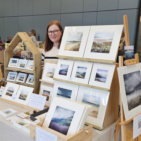 artist standing in front of display of scottish art prints How To Display Canvas Art At Craft Show, Art Market Display Booth Ideas, Print Display Ideas, Art Vendor Booth Ideas, Art Market Booth, Art Show Display Ideas, Art Market Display, Market Displays Booth Ideas, Art Exhibition Ideas