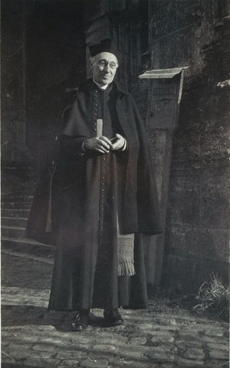 9. Chausable's name is a type of vestment worn by Catholic Priests. He is a reverend in 1800s London. An appropriate costume would be a cassock and clerical collar.   unknown. Prelate standing outside in front of a cathedral entrance. He wears a cassock, shoulder cape, cloak, and headgear. His cincture is visible.. n.d. (circa 1916-1920). Artstor, library.artstor.org/asset/SCHLES_130740359 Clerical Collar, 1800s Priest, Evil Priest Aesthetic, Cassock Aesthetic, Victorian Priest, The Stranger Albert Camus, Priest Costume, Priest Outfit, Traditional Catholicism