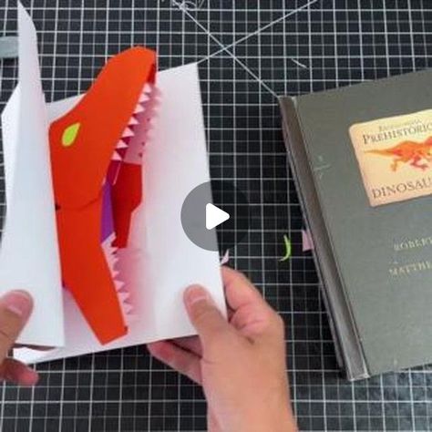 Matthew Christian Reinhart on Instagram: "Welcome to pop-up class, students! May is Dinosaur Month for us here on my channel, so I thought I'd share with you how I made one of my most iconic dinosaur pops from my NYTimes best-selling book 'Encyclopedia Prehistorica - Dinosaurs' - the chomping Tyrannosaurus Rex. Let's go through each step together and build a big biting pop-up carnosaur from scratch!

Learn to make your own:
https://youtu.be/qiTAdmeOkCo?si=QYb3deUzmCDMhOpF" How To Make A Dino Out Of Sticky Notes, 3d Dinasour Craft, Dinosaur Pop Up Card Diy, 3d Dinosaur Paper Craft, Pop Up Dinosaur Card, Never Touch A Dinosaur Book, Dinosaur Cards, Selling Books, Pop Up Book