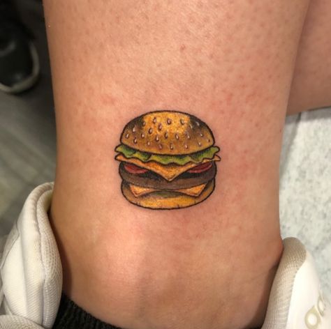 This is a fast-food tattoo of a burger. If you enjoy eating burgers, you should show your affection for them by getting a burger design tattooed on your body. This bright burger tattoo adds a realistic and feminine touch to... Sandwich Tattoo, Burger Tattoo, Burger Design, Food Tattoos, Tattoo Color, Ankle Tattoo, Couple Tattoos, Infinity Tattoo, Cheeseburger