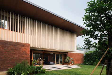 Located in the heart of South Jakarta, this house was designed as a response to the tropical climate. The building consists of 3 main masses, the front is the semi-public area which includes a garage, service area, powder room, and working room. The front part is a brick rectangular box with a compressed wooden ceiling, creating a transitional entrance to the main area. Every room is designed with a big opening to have good air circulation and natural light. Big Balcony, Mid Century Exterior, Studio 17, Floating Stairs, Wooden Ceilings, Patio Designs, Big Windows, Modern Tropical, Tropical Houses