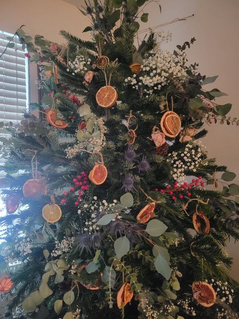 Christmas tree decorated with flowers and dried citrus! Fall Decorated Apartment, Dried Fruit Christmas Tree Decorations, Floral In Christmas Tree, Tree Decorated With Flowers, White Christmas Tree Vintage, Dry Flowers Christmas Tree, Dried Flowers In Christmas Tree, Yule Themed Christmas Tree, Tensile Christmas Tree