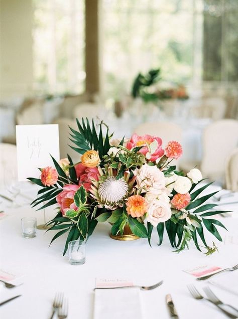 Tropical wedding centrepiece with palm leaves, protea and peony in coral, orange, pink and yellow | Hannah Mayson Photo via 100 Layer Cake Tropical Wedding Centerpieces, Tropical Centerpieces, Tropical Wedding Theme, Tropical Wedding Inspiration, Tropical Wedding Flowers, Flowers And Greenery, Wedding Floral Centerpieces, Coral Wedding, Beach Wedding Favors