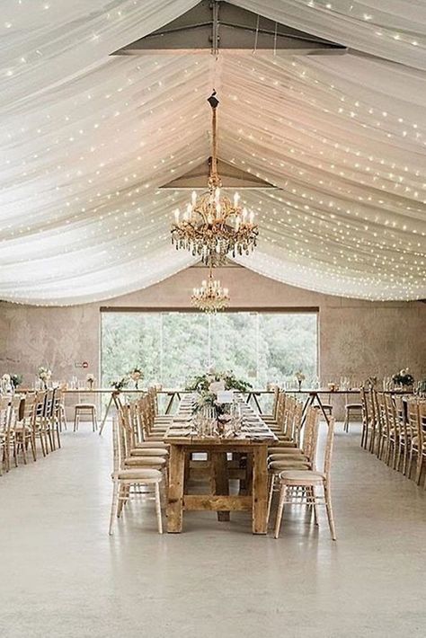 wedding reception decorations in a barn the ceiling is decorated with a white cloth with lights and chic golden chandeliers and long tables charlotte elise events via instagram by summer Reception Ceiling, Wedding Ceiling Decorations, Reception Decorations Wedding, Wedding Draping, Draping Wedding, Wedding Ceiling, Ceiling Draping, Ceiling Decorations, Indoor Wedding Receptions