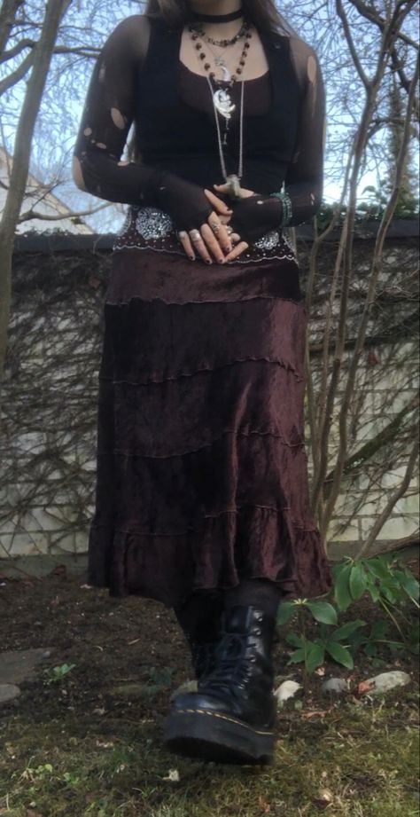 A mid-size person/girl wearing mate rose lipstik, a black tight waistcoat with a ripped stocking selfmade longsleeve and a thrifted dark brown maxi skirt, black dr. Martins and multiple crystal rings and bracelets. 	The person is also wearing multiple silver necklaces, one in form of a dragonfly and another in form of a moon, a green crystal bead necklace and a black lace choker. Fairy Goth Outfit, Fit Aesthetic Outfit, Goblin Forest, Grunge Fairycore Outfits, Dryad Costume, Ripped Stockings, Grunge Plus Size, Fem Style, Fairy Grunge Outfit