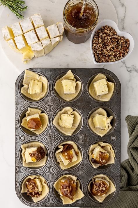 antique muffin pan filled with unbaked brie bites, topped with fig jam and walnuts Fig And Brie Bites, Brie Bites Puff Pastry Fig, Appetizers Using Fig Jam, Fig Brie Bites, French Onion Brie Puffs With Fig Jam, Baked Brie With Fig Jam Puff Pastry, Brie Fig Jam Appetizer, Fig Brie Puff Pastry, Brie Fig Appetizer