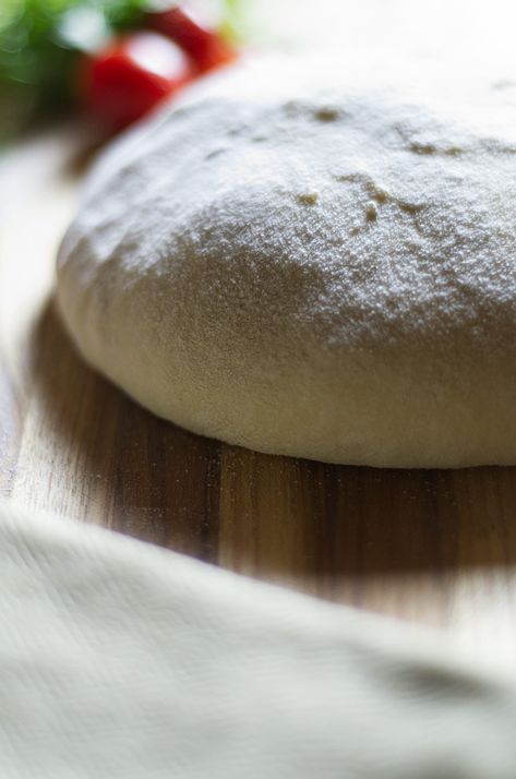 A mound of raw pizza dough sitting on a floured board with some fresh tomatoes and basil in the background. Slow Rise Pizza Dough, Cold Fermented Pizza Dough, Active Dry Yeast Pizza Dough, Homemade Pizza Dough Active Dry Yeast, No Knead Pizza Dough, The Practical Kitchen Pizza Dough, Best Pizza Dough Recipe, 70% Hydration Pizza Dough Recipe, Best Pizza Dough