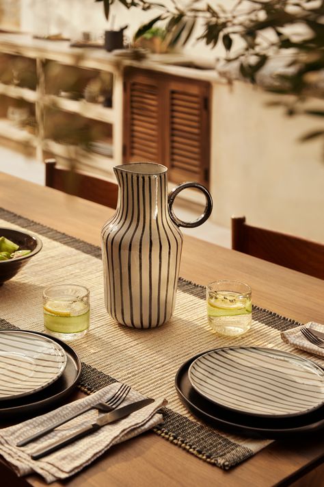 A stylish table setting with black tableware and a large, handpainted jug. Tableware Photography, Small Wooden Tray, Rustic Tableware, Modern Tablescape, White Tableware, Large Plant Pots, Patterned Napkins, Table Setting Inspiration, Dinner Table Setting