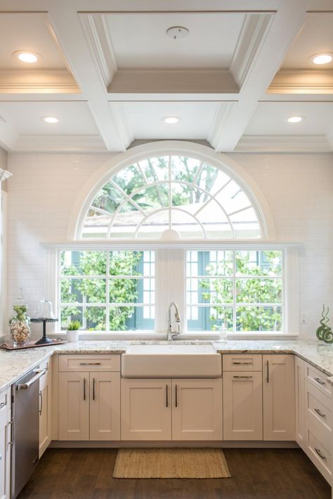 A beautiful half circle window is a worthy centerpiece in this sophisticated kitchen with a warm, updated farmhouse feel. A farmhouse sink, subway tile surrounding the window and coffered ceiling all work in stunning symmetry creating a stylish and comfortable feeling of history. Arched Window Over Kitchen Sink, Round Windows Ideas, Half Circle Window, Unique Windows, Updated Farmhouse, Circle Window, Sophisticated Kitchen, Beautiful Settings, Circle Arch