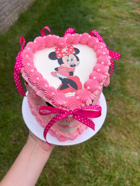 Heart shaped cake with white frosting, rich pink piped borders topped with small edible pearls. A picture of Minnie Mouse is on the center of the cake, she’s wearing her iconic pink polkadot bow. Large pink polka dotted bows line the edges of the cake. Minnie Mouse Butterfly Cake, Minnie Mouse Birthday Party Ideas Cake, Minnie Mouse 1st Birthday Cake, Minnie Mouse Cake Design, Minnie Mouse Smash Cake, Minnie Mouse Birthday Cake, Minnie Mouse Birthday Cakes, Minnie Cake, Minnie Mouse Cake