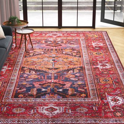 This boho-inspired area rug takes inspiration from traditional Persian textiles for a classic look. A central medallion design features a geometric motif and intricate border, in red and navy blue with just the right amount of fading. Power-loomed from polyester, it has a low 0.16" pile height that makes this rug an ideal base for busy spaces. This rug includes a non-slip backing to help it stay put. Best of all, this rug is stain-resistant, so holds up to regular use and its material makes it r Red And Blue Area Rug, Colorful Persian Rug, Blue Couch Red Rug, Navy Blue Room Red Rug, Overlapping Rugs, Red Boho Rug In Bedroom, Red Boho Rug Bedroom, Red Living Room Rug, Red And Blue Rug