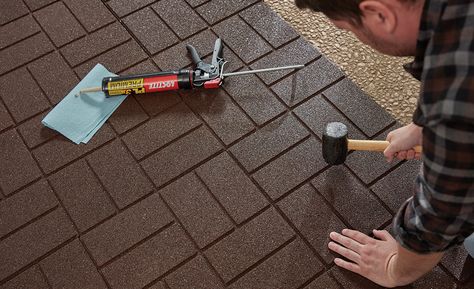 A man setting rubber pavers with a mallet. Rubber Pavers Ideas Patio, Recycled Rubber Pavers, Diy Stone Walkway, Rubber Pavers, Rubber Paver, Paver Ideas, How To Install Pavers, Brown Tile, Paver Tiles