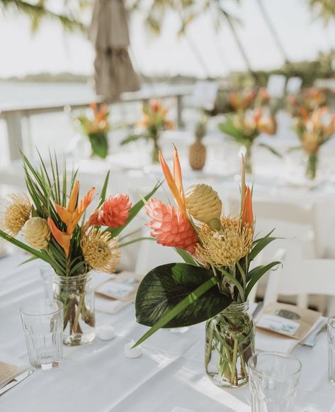 Mason Jar Tropical Centerpieces, Tiki Wedding Centerpieces, Tropical Floral Arrangements Simple, Tropical Floral Table Arrangements, Tropical Flower Table Arrangements, Hanging Flower Lights, Hawaii Table Decorations, Railing Decorations Party, Small Tropical Floral Arrangements