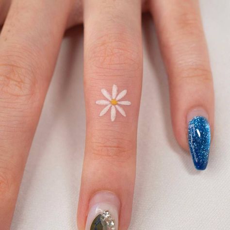 Minimalist daisy flower tattoo on the finger. Flowers On Finger Tattoo, Small Daisy Tattoo Color, Tiny Flower Finger Tattoo, Small Flower Tattoos Finger, Daisy Tattoo On Finger, Daisy Tattoo Finger, Micro Daisy Tattoo, Finger Tattoos Colorful, To Do List Tattoo