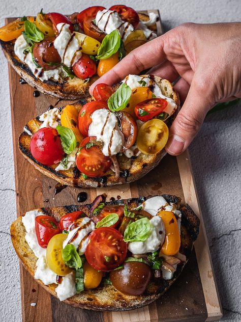 Bruschetta topped with cherry tomatoes, cheese and herbs. Bruschetta And Burrata, Appetizers With Burrata Cheese, Burrata Presentation, Italian Food Easy, Summer Burrata Board, Bistro Lunch Ideas, Bruschetta Presentation, Recipes With Baratta, Romantic Finger Food Ideas