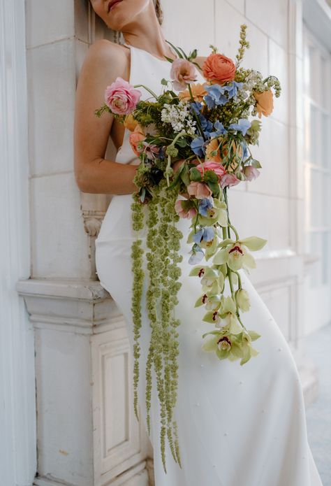 Elegant cascading wildflower bouquet held by the bride wearing a simple white wedding gown. Artistic Wedding Bouquets, Tulip And Wildflower Bouquet, Wedding Bouquet Hanging Flowers, Droopy Bridal Bouquet, Wildflower Wedding Bridesmaids Green, Colorful Cascading Bouquet, Colorful Cascade Wedding Bouquet, Wedding Bouquet Hanging, Dangling Wedding Bouquet