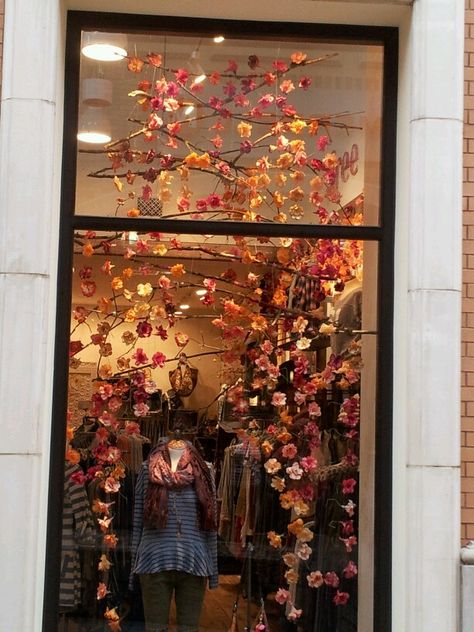 Free People window display. It would be fun to do a wall like this inside with branches hanging across with artificial flowers (or some colorful fall leaves) hanging down by string. Fall Storefront Window Display, Autumn Shop Window Display, Fall Window Display Store Fronts, Fall Window Displays, Fall Window Display, Charity Shop Display Ideas, Easter Window Display, Autumn Window Display, Fall Window Boxes