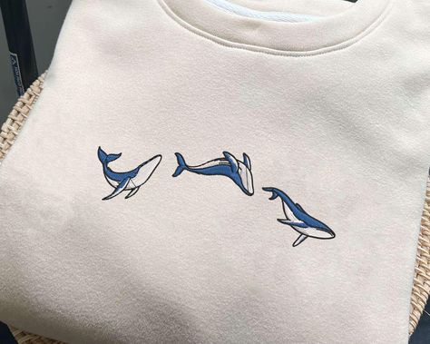 Blue Ocean Whale Embroidered Sweatshirt, Whale Shark embroidery Crewneck, Respect The Locals, Nature Lover Gifts, Save the ocean shirt This sweatshirt is crafted from high-quality cotton weave and features advanced embroidery technology to ensure vibrant colors and intricate patterns. It's unisex, soft, and comfortable, making it perfect for a stylish, casual look. Each sweatshirt boasts a unique aesthetic, making it a timeless gift for family, friends, or teachers. Size: We offer a range of col Ocean Inspired Outfits, Whale Embroidery, Ocean Life Embroidery, Whale Shark Embroidery, Embroidery Ocean Theme, White Crew Neck Top With Shark Design, Whale Shirt Aesthetic, Embroidery Crewneck, Ocean Shirt