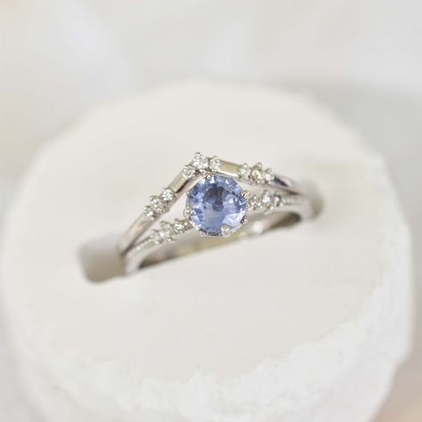 Discover the perfect symbol of love and commitment with our magical pastel blue sapphire engagement ring. The 0.75 carat blue sapphire sits elegantly in a solitaire setting, surrounded by 8 round prongs and set on a 14k white gold band with two sets of 3 round graduated side diamonds add the perfect touch of sparkle to this beautiful and elegant design. Make your proposal unforgettable with this timeless piece. White Saffire Engagement Rings, White Gold Sapphire Engagement Ring, Engagement Rings Silver Blue, Sapphire Engagement Ring Silver, Sapphire Solitaire Engagement Ring, Blue Wedding Rings, Light Blue Sapphire, Blue Sapphire Engagement Ring, Sapphire Engagement Rings