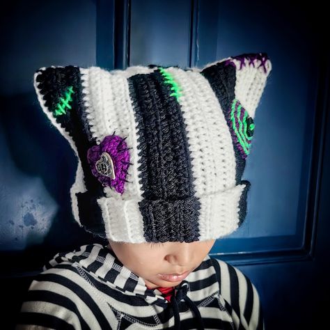 Handmade crochet cat beanie with cat ears with ribbing, buttons, and stitching details. Size: For elderly emo heads 21+ inch in circumference. May fit emo child's head loosely. Length is 9-10 inches long for folding outwards if preferred. Color: black and white stripes with purple and bright green details. Color may vary slightly due to monitor settings. Stitch design and placements may vary slightly as each one is handmade by moi. Materials: acrylic yarns (stretchy) and buttons  Made to order i Sally Nightmare Before Christmas Hat, Crocheted Halloween Hats, Odd Crochet Patterns, Tapestry Crochet Hat, Halloween Crochet Beanie, Crochet Goth Clothes, Halloween Crochet Hats, Cat Ear Beanie Crochet Pattern, Animal Crochet Hat