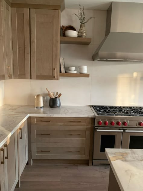 Organic Modern Kitchen Shelves, Alaska Kitchen Design, Cool Tone Wood Kitchen Cabinets, Organic Looking Kitchen, Floating Shelves By Stove, Natural Wood Kitchen Cabinets With Stainless Steel Appliances, Organic Modern Countertops, Kitchen Cabinet Panels Ideas, 2 Tone Wood Kitchen Cabinets