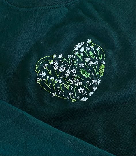 embroidery, sweater, handmade gift, embroidered heart, green sweater, dark green, flowers, stiched flowers, simple embroidery, embroidered sweater, DIY embroidery kit, handmade style, sweater weather, creative craft, embroidery project, cozy vibes, DIY fashion, craft kit, personalized clothing Embroidery On Dark Green Fabric, Embroidered Sweater Diy, Dark Green Flowers, Dark Green Shirt, Flowers Simple, Sweater Handmade, Diy Sweatshirt, Embroidery Sweater, Embroidery Hoodie