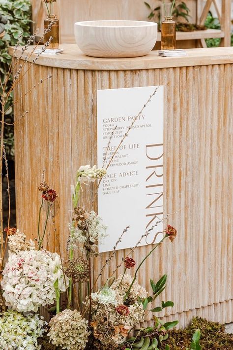 This rustic bar setup is perfect for a garden party or outdoor wedding. A wooden bar adorned with vibrant floral arrangements creates a charming focal point, while a simple white drink menu adds elegance. The relaxed and inviting aesthetic blends rustic charm with floral sophistication, making it an ideal inspiration for outdoor event decor. rustic bar setup, outdoor wedding, floral arrangements, drink station, wooden bar, wedding inspiration, event decor, rustic elegance, outdoor party ideas. Wedding Trash Can Ideas, Wooden Bar Wedding, Wedding Water Station, Outdoor Events Decor, Outdoor Wedding Bar, Mobile Bar Business, Inviting Aesthetic, White Drinks, Outdoor Party Ideas