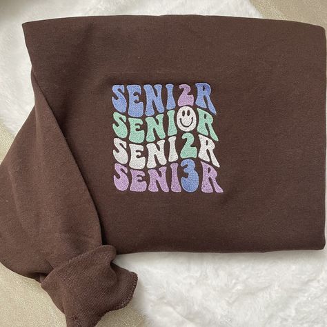 2023 Senior Embroidered Sweatshirt. Hello there! Please message me if you have any additional questions or want to change thread colors. We are a family-run Etsy page; my husband and I make all orders from home. You can also send us a message if you would like a custom sweatshirt/t-shirt with whatever words and images, and we will see if we can accommodate your order! HOW TO ORDER - Please Choose the SIZE and COLOR From Drop Down Menu. MATERIAL - We use JerZees as our blanks; I may sometimes sub Senior Sweaters Design, High School Merch Ideas, Senior Nails Ideas 2024, Senior Merch Ideas, Graphic Embroidered Crew Neck Sweatshirt For School, Senior Hoodie Ideas, Senior Sweatshirts Ideas Diy Patches, Senior T Shirts, Custom Embroidery College Hoodie Sweatshirt