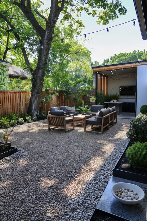 Modern backyard seating area with wooden furniture on a pea gravel patio, shaded by trees. Includes outdoor lighting and decor. Perfect for a backyard getaway. In Ground Patio Ideas, Backyard Landscaping Easy Maintenance, The Perfect Backyard, Outdoor Furniture On Gravel, Mulch Patio Ideas Backyards, Garden Design Gravel, Side Yard Pea Gravel, Small Backyard Xeriscape Ideas, Low Maintenance Gravel Garden