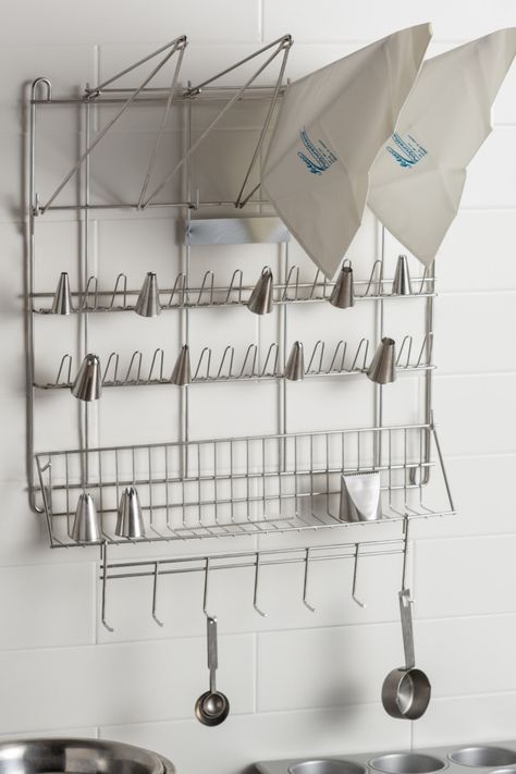 Kitchen organization is a top priority when trying to get your business to run smoothly. Whether you own a bakery or your restaurant has a top-tier pastry team, having a pastry bag and pastry tip drying rack is beneficial for cleaning and organization. This drying rack makes storage simple, too! Pot Storage Small Space, Pantry Apron Hangers, Anthropology Holiday Cooling Racks, Balcony Grocery Hoist, Soap Making Drying Racks, Bakery Organization, Bakery Layout, Baking Supplies Organization, Baking Room