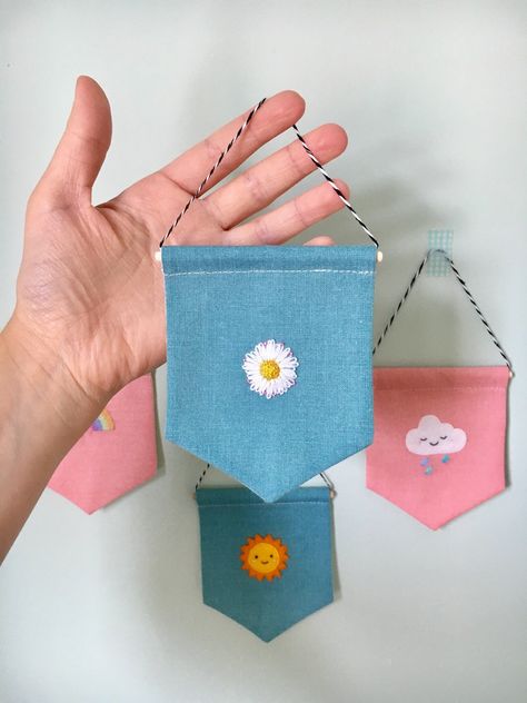 Bring some spring to your feature wall with this unique mini hand embroidered wall hanging. It has been completely hand made to my own design and features three different embroidery stitches to make up the realistic daisy on blue cotton fabric. The pennant measures 8.7 centimetres wide by 10.8 centimetres tall and hangs at approximately 6 centimetres from the top of the hanging thread. This wall hanging is made for decoration only and is not suitable for children to play with due to small parts. Embroidery Banner Wall Hangings, Embroidered Wall Decor, Embroidery Hanging Wall, Fabric Wall Decor Diy, Simple Embroidery Gifts, Framed Fabric Wall Art Ideas, Hand Embroidery Gifts, Small Embroidery Designs, Wall Hanging Fabric